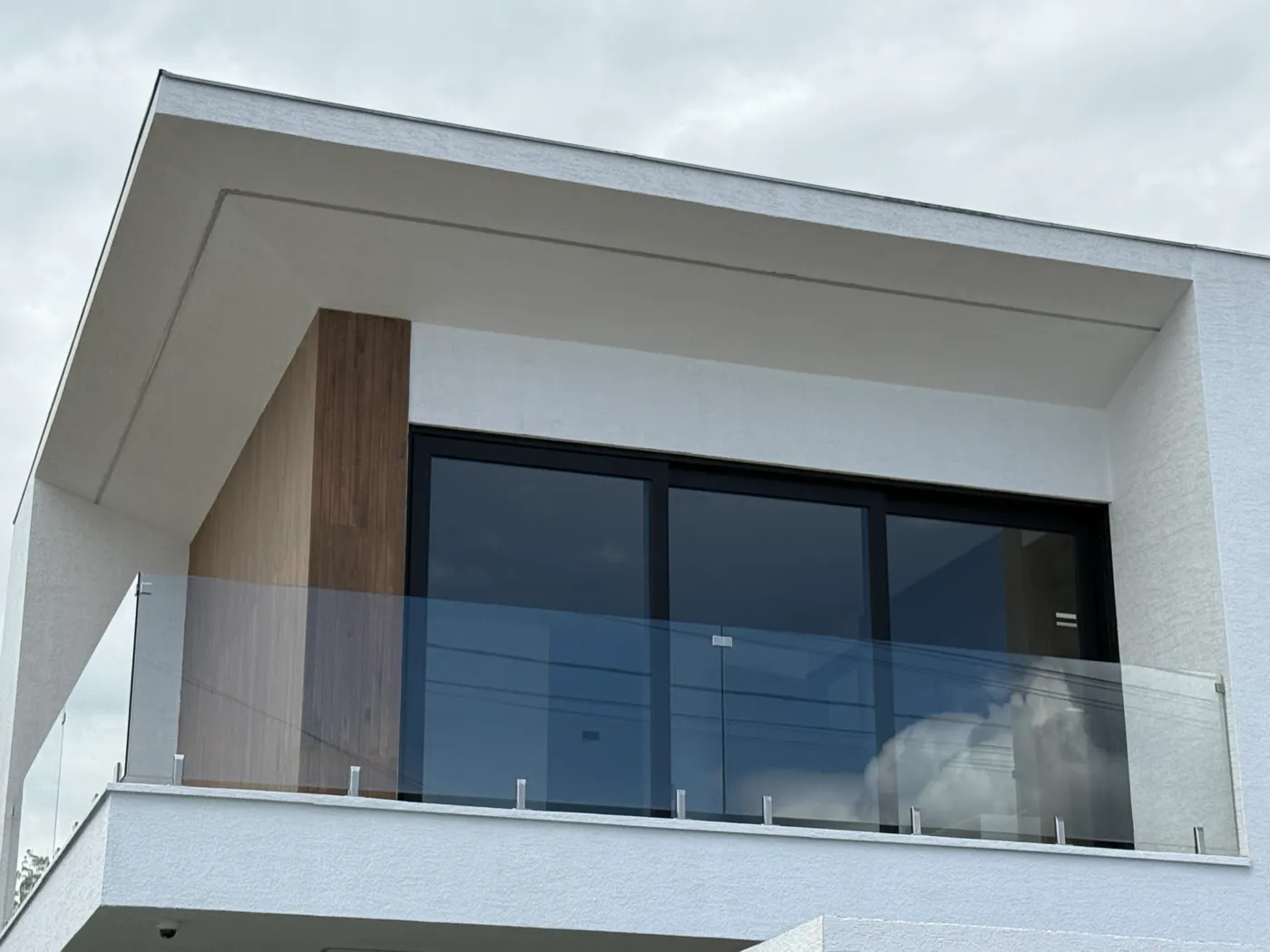 Balcón moderno con barandilla de vidrio templado y ventana corrediza