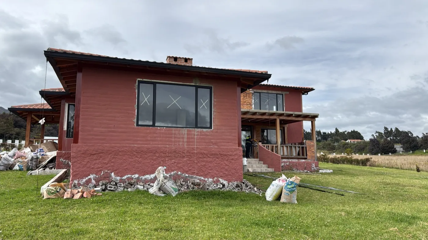 Casa de campo de dos pisos con acabado rojo y amplio jardín