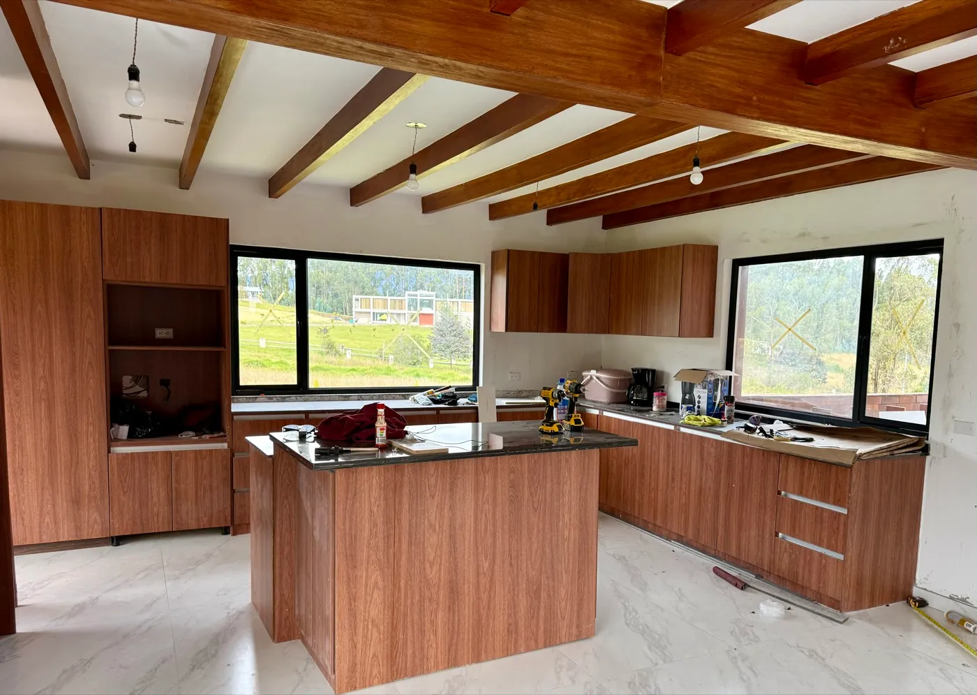 Cocina terminada con muebles de madera, isla central y vigas vistas