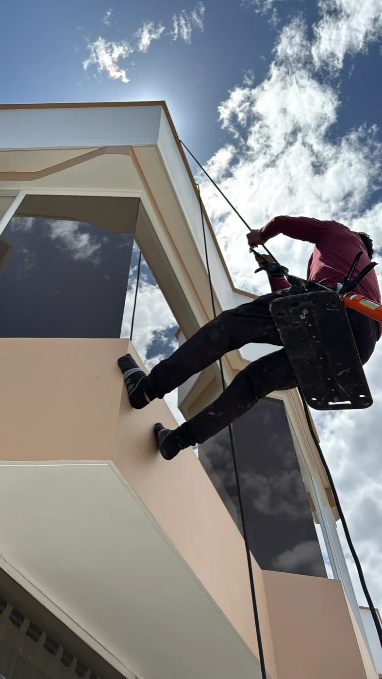 Técnico de Construvid instalando vidrio de fachada suspendido con cuerdas